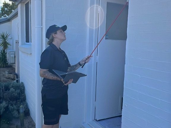 Person using an inspection tool near a doorway while holding a tablet